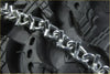 Shiny metallic v-bar tire chains with interlocking links wrapped around rugged black tire for suzuki quadsport z400