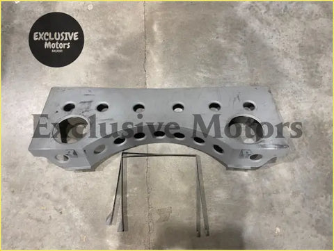 Gray metallic alloy tank mounting bracket engine block with multiple holes and curved design visible from back side