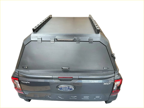 Black matte aluminum hardtop canopy with led light bar and side rails mounted on ford ranger xlt back side view