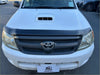 White toyota hilux pickup truck with matte black bonnet guard featuring a black grille and hood scoop