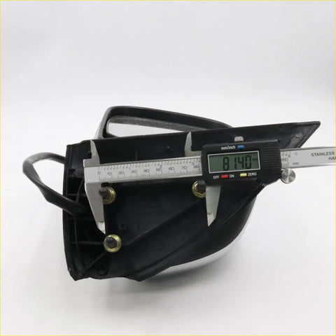 Black plastic back side of chrome electric door mirror housing with metallic fasteners and digital caliper for Toyota Hilux