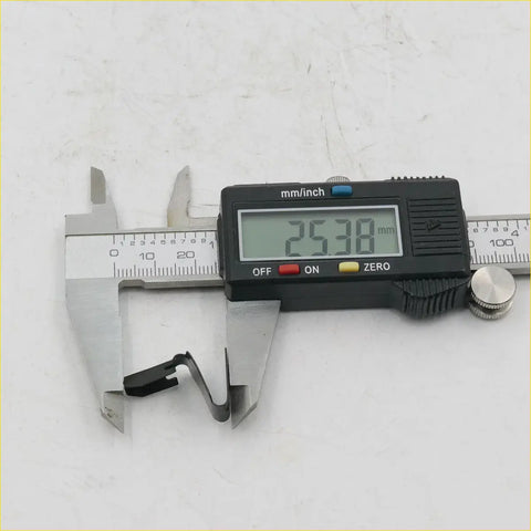 Black digital caliper measuring a 25.38 mm black metal door panel clip for nissan datsun bluebird 1963-1973
