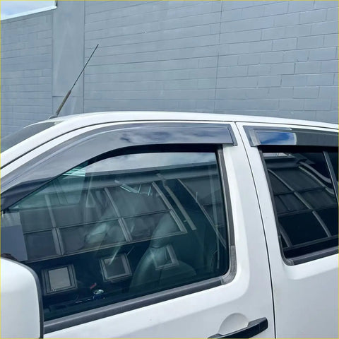 Black plastic door visors window monsoons weather shields installed on white nissan navara d40 pickup truck windows