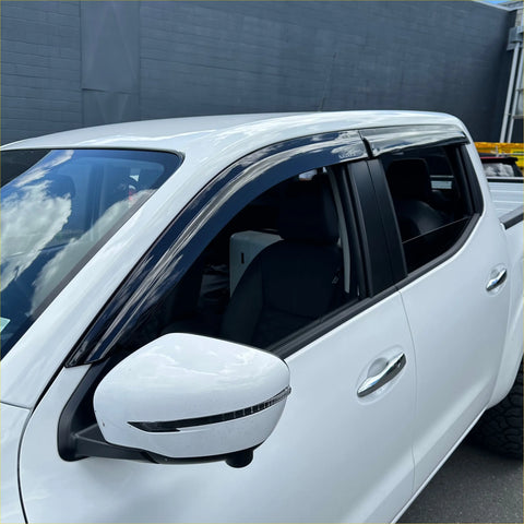 Black plastic door visors installed on white nissan navara np300 pickup for weather shield protection
