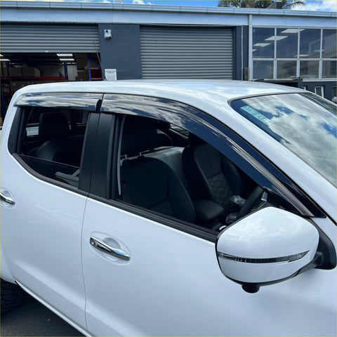 Black plastic door visors window monsoons weather shields installed on a white nissan navara np300 vehicle