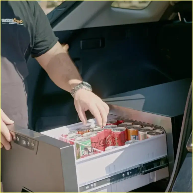 Silver-framed compact car fridge with digital temp display and sliding drawer filled with soda for ute and offroad use