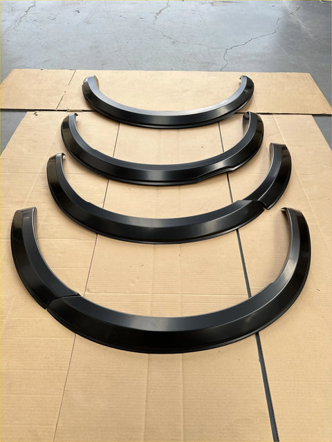 Matte black glossy 4-inch aftermarket fender flares for isuzu d-max 2024 arranged descending on cardboard