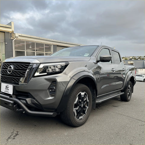 Gray metallic nissan navara pickup with 4-inch matte black fender flare and rugged front bumper with black alloy wheels