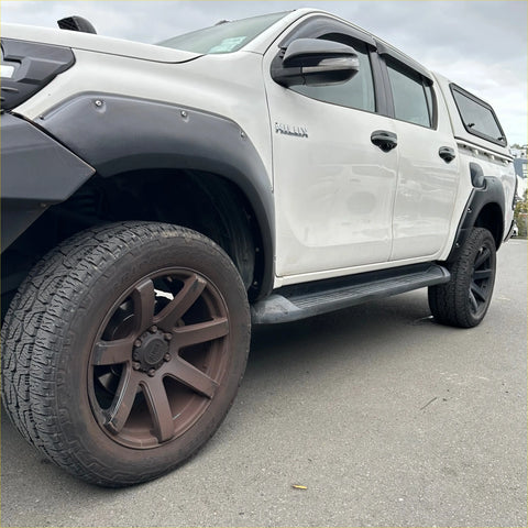 White toyota hilux rocco 2018-2020 with black lychee texture fender flares and roof rack from the back side