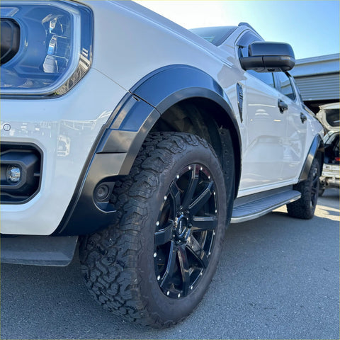 Black multi-spoke alloy wheel with silver accents and rugged off-road tire on white ford ranger 2022 fender flare model