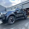 Black matte bolt style fender flare on a glossy black nissan navara 2021 with black alloy wheels