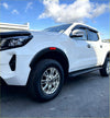 White nissan navara 2021+ with matte black oem style fender flares and chrome alloy wheels front side view