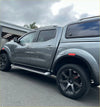 Gray metallic nissan navara pickup with black alloy wheels and hardtop canopy featuring red layer fender flare oem style