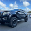 Black nissan navara np300 2015-2020 with chrome bolt style fender flares and rugged off-road tires from the back side