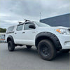 White toyota hilux vigo 2005-2012 with black bolt style textured fender flares and roof rack shown from the side