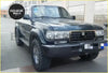 Dark green metallic toyota land cruiser 100 with chrome front bumper radiator grille and rugged off-road tires