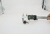 Black plastic carabiner being measured with digital caliper for front window washer nozzle on nissan