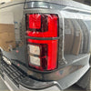 Black truck taillight cover with red and clear lenses in matte rugged gray plastic bezel for mitsubishi triton 2024+