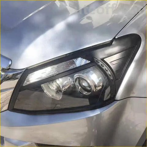 Black headlight covers with clear lens and chrome accents for isuzu d max 2012-2016 mounted on silver car body