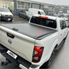 Black retractable manual roller shutter tonneau cover on white nissan navara np300 pickup truck back side view
