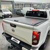 Black manual roller shutter tonneau cover on the back of a white nissan navara np300 pickup truck