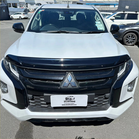 White mitsubishi triton pickup with black front grille and chrome emblem featuring monsoon bonnet guard 2019-2023