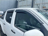 Black plastic window visors installed on a white Nissan Navara D40 2005-2015 with Monsoon and bonnet guard