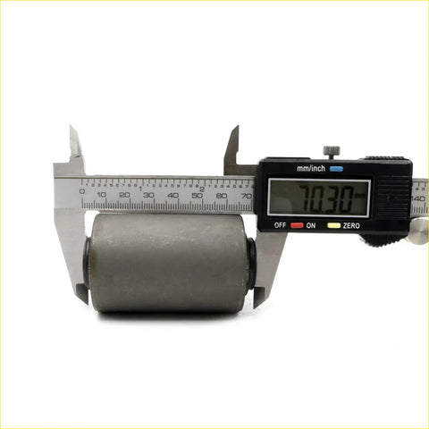 Gray cylindrical roller with matte finish measured by digital caliper for rear spring front bush assembly on Nissan 620