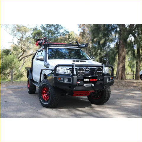 White toyota hilux 4wd ute with black red rockarmor brushbar bumper roof rack and red alloy wheels for offroad use