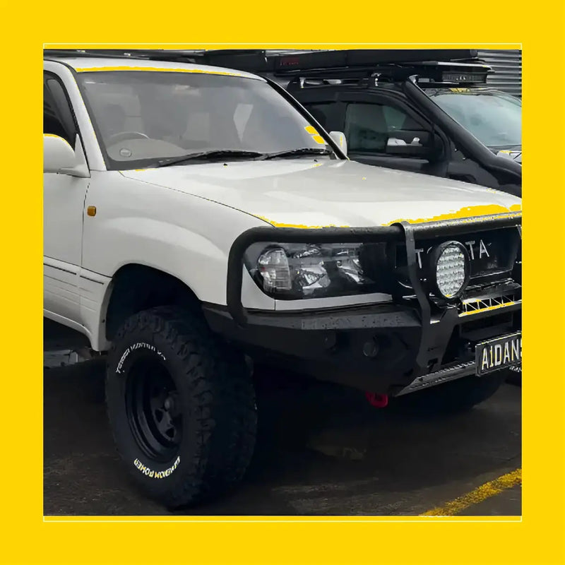 White toyota land cruiser with black steel rockarmor gt hoop bullbar and off-road tires for 105 series 98-07