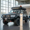Black nissan patrol suv with rockarmor gt hoop steel bullbar full bar replacement, offroad 4wd with rugged tires and roof rack gear