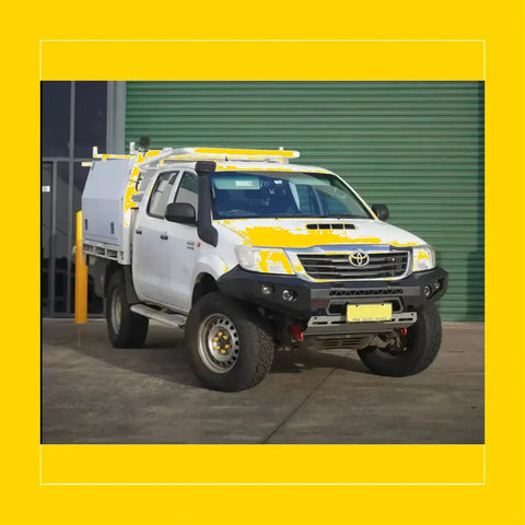 White toyota hilux with yellow accents featuring rockarmor gt hoopless steel bullbar for off-road protection