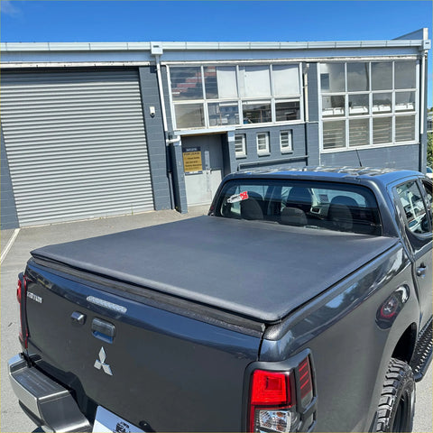 Black fabric soft tonneau cover on the back side of a mitsubishi triton 2015-2023 double cab pickup truck