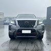 Silver nissan navara pickup with stainless steel black nudge bar and illuminated headlights front view