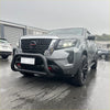 Gray nissan navara with black front bumper guard and rugged tires featuring stainless steel medium size nudge bar