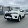 White toyota hilux pickup truck featuring a matte black stainless steel nudge bar and black front bumper guard