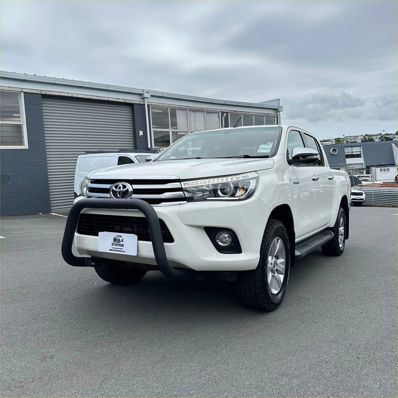 White toyota hilux pickup truck featuring a matte black stainless steel nudge bar and black front bumper guard