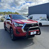 Red toyota hilux pickup with a matte black stainless steel nudge bar and black front bumper guard with chrome accents