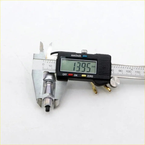 A metallic spark plug with a black tip measured by digital caliper for nissan datsun 1500 stop light brake switch
