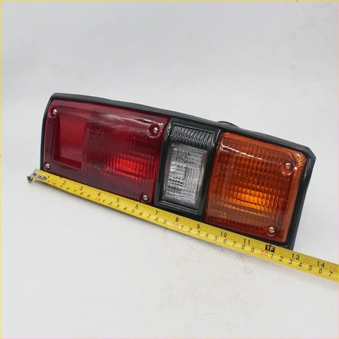 Black plastic tail light for Toyota Hilux 1978-1983 with red amber and clear lens sections shown from back side
