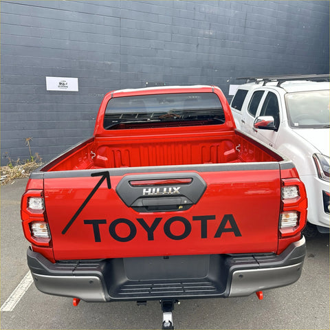 Back view of a red Toyota hilux 2021 with a textured black tailgate cover featuring black Toyota logo and silver trim
