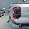 Back side of silver metallic ford ranger 2022 with matte black taillight covers and modern red taillight trim
