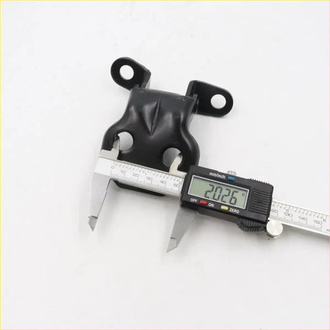 Black rubber engine mount with two circular mounting tabs being measured by caliper for toyota hilux door hinge