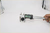 Black digital caliper measuring a small black cylindrical washer jet nozzle for datsun nissan 620 720 521 1968-1985